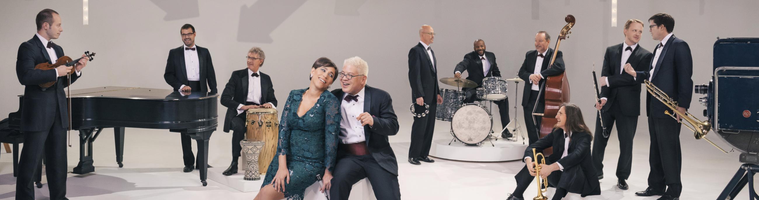 white room with people in suits and dresses standing around looking at each other