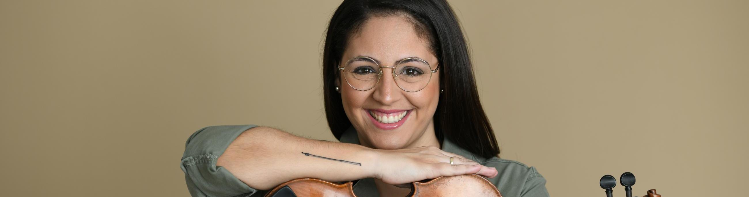 woman with dark hair holding a violin smiling