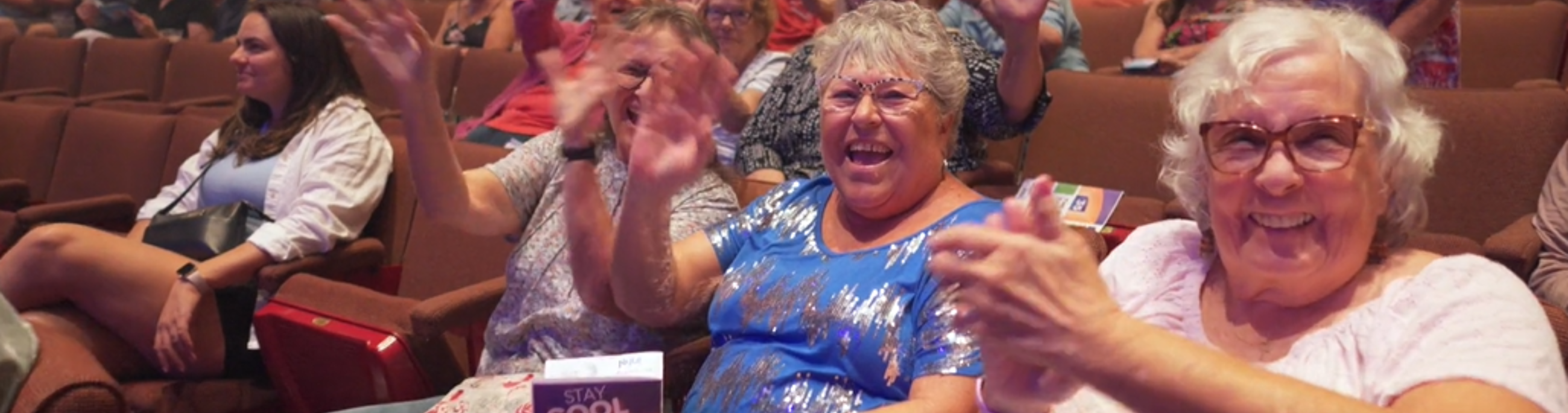 Group of women sitting in the CCA theatre, clapping and enjoying the Free Summer Concert Series