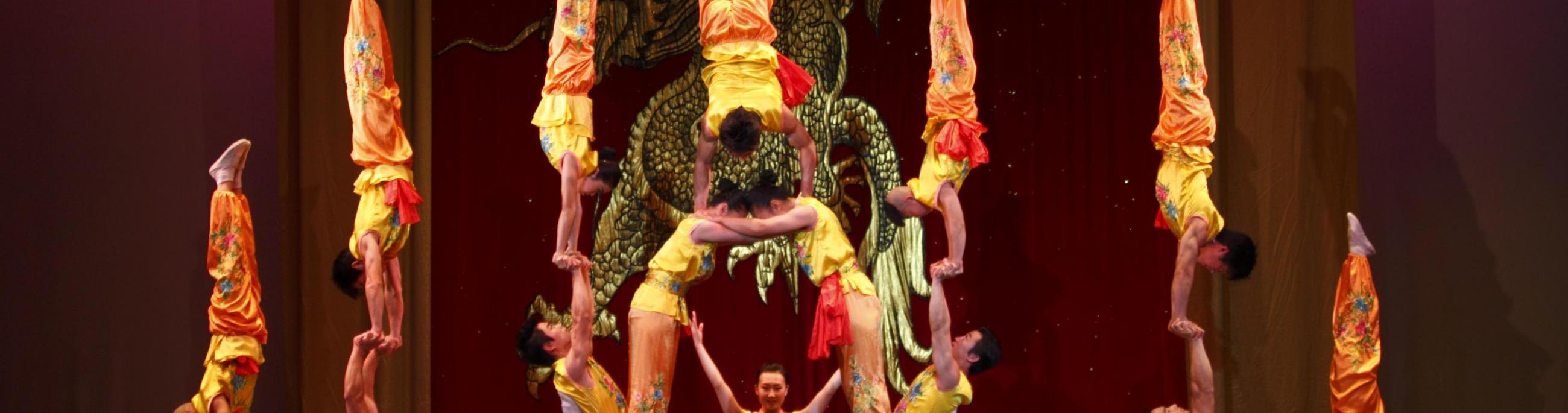 people holding up one another in handstands, making a triangle