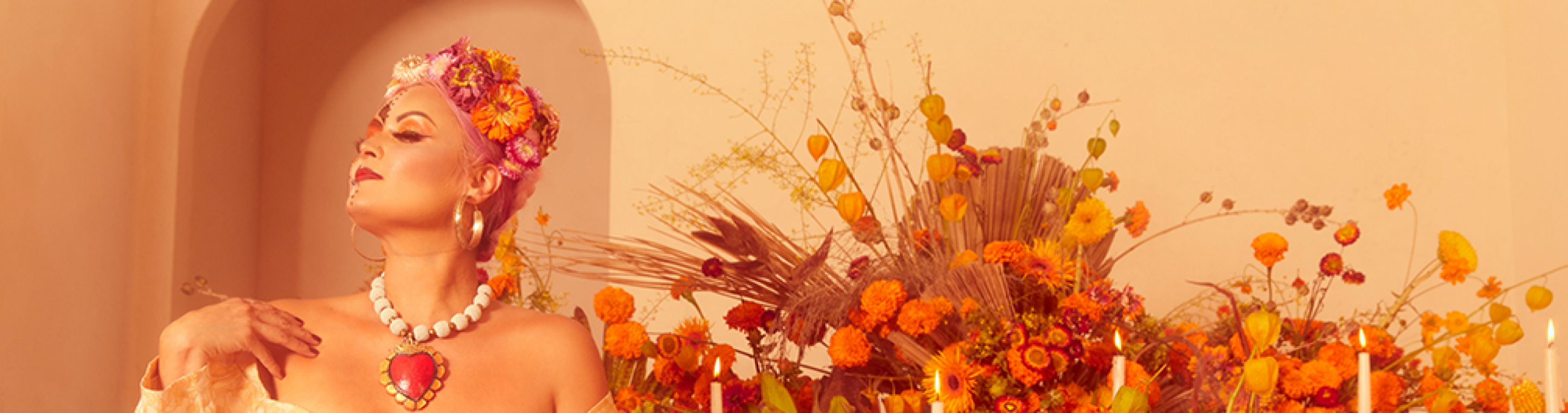 A woman sits in front of an abundant display of orange flowers