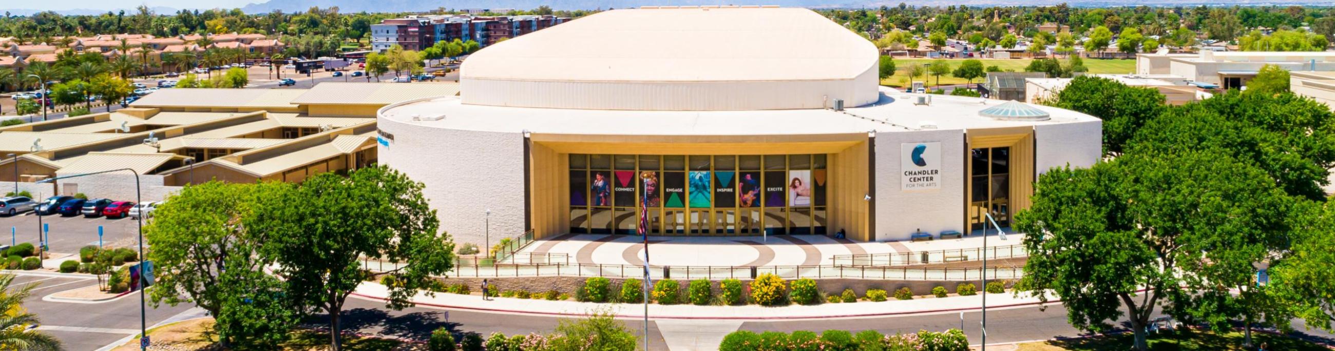 The CCA performing arts building with trees on either side, grass in front and a blue sky above. 