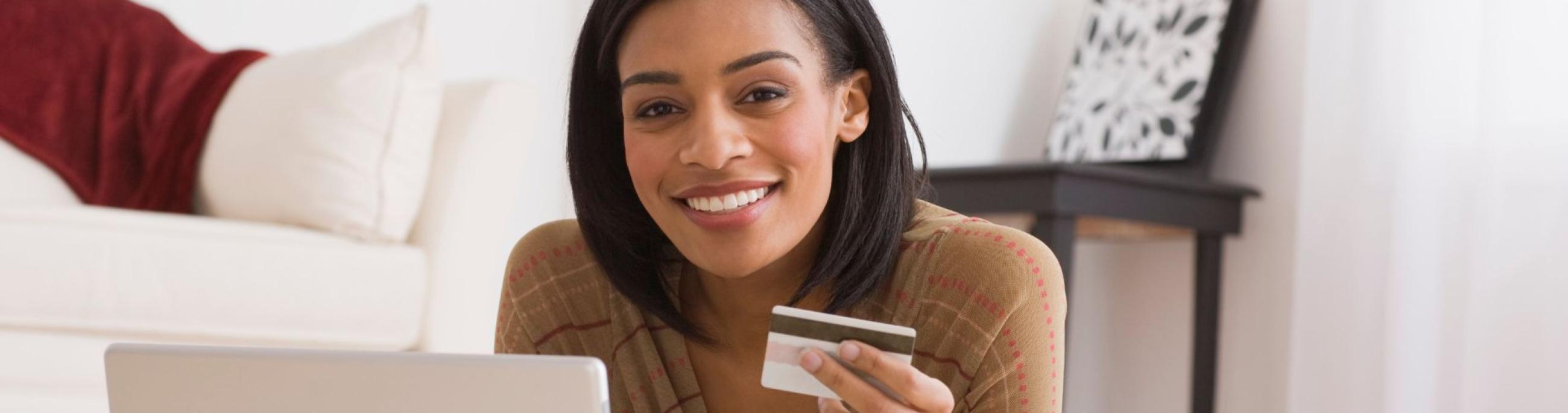 black woman with credit card looking at the computer smiling