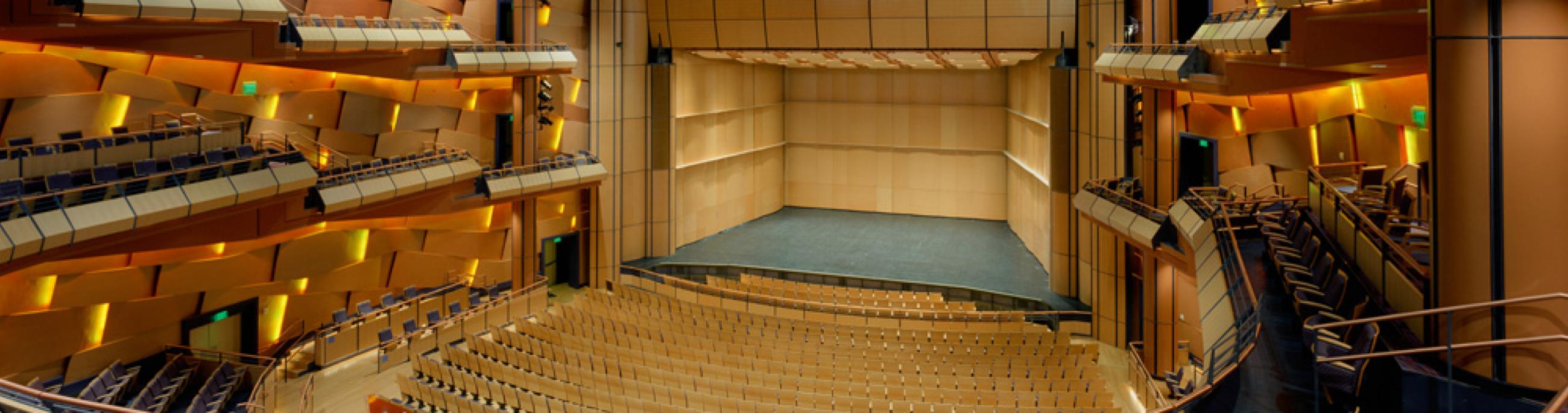 Panoramic photo of a theatre with the main stage at the center and seats surrounding it