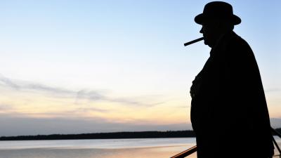 A man stands in silhouette against a sunset over the water