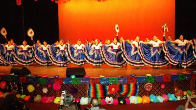 A line of Ballet Folklorico dancers in blue skirts with colorful trim.