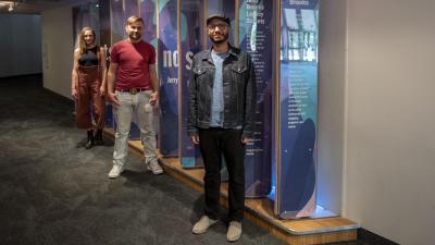 Local Artists Safwat Saleem, Ben Lewis and Chelsea Hickok stand in front of the interactive donor wall at the CCA