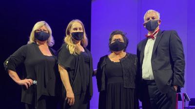 Four musicians, dressed in formal wear and masks, pose in front of a purple backdrop.