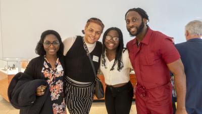 Four people pose, arm in arm, smiling at the camera