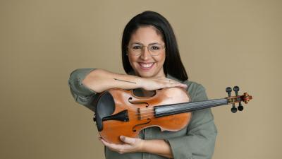 woman with dark hair and glases holding a violin 