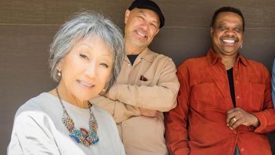 A woman and four men pose with a Japanese string instrument