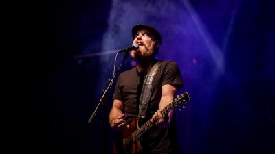 man with a beard in the spotlight singing into a microphone