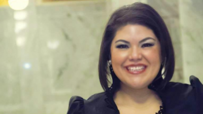 A woman in a black blouse and silver earrings smiles at the camera.