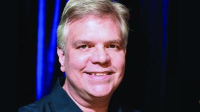 A man with short gray hair smiles at the camera