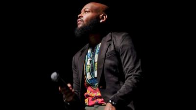 Man sitting in a dark room with a microphone looking off to the left