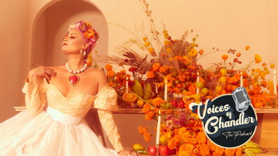 A woman sits in front of an abundant display of orange flowers