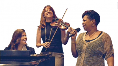 A pianist, violinist, and singer perform in front of a white background.