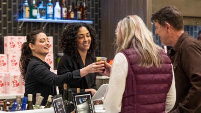 two bartenders serving customers 