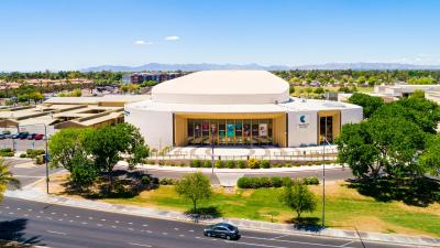 The CCA performing arts building with trees on either side, grass in front and a blue sky above. 