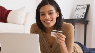 black woman with credit card looking at the computer smiling