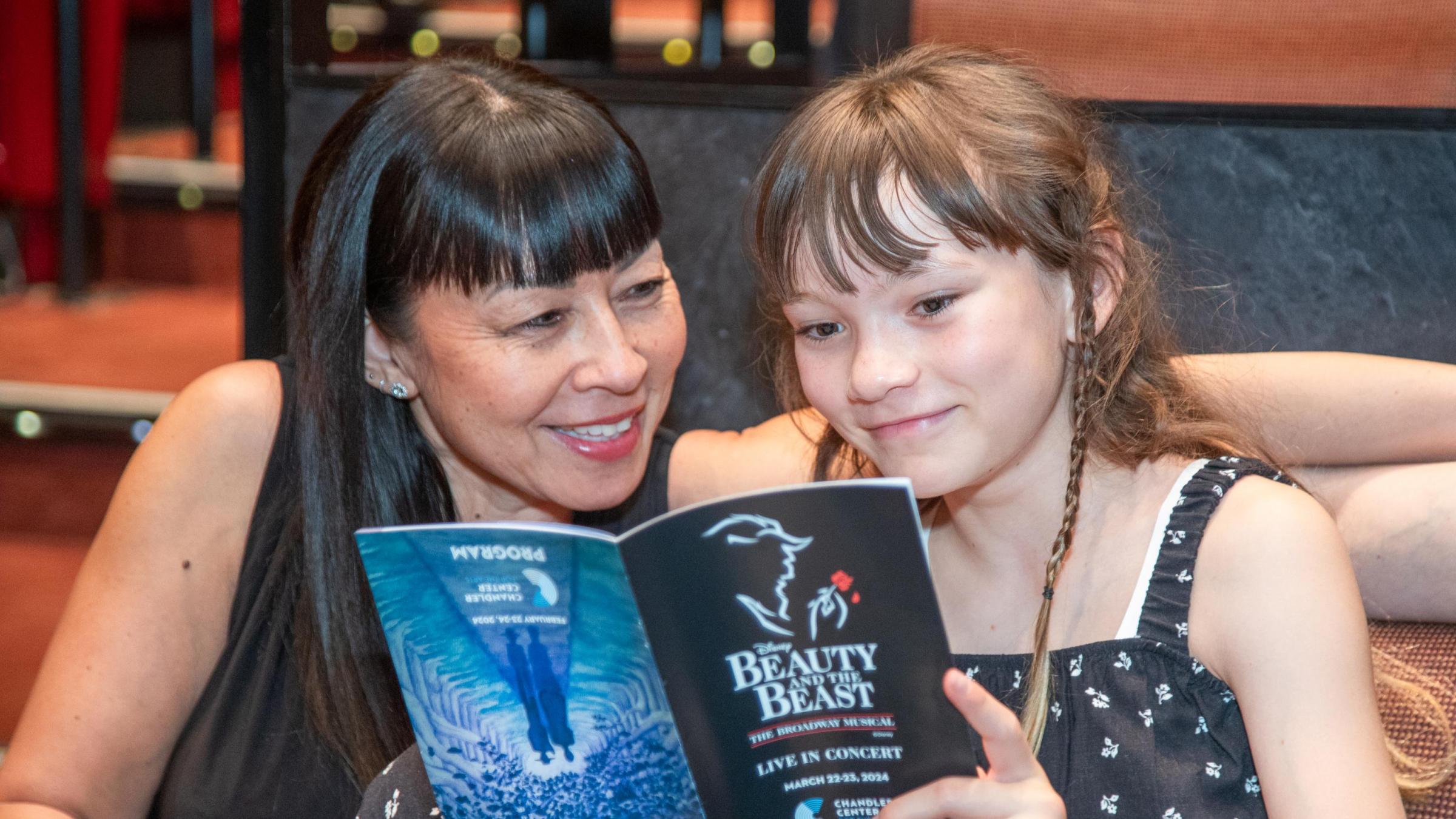 Adult and child smiling at Beauty and the Beast program