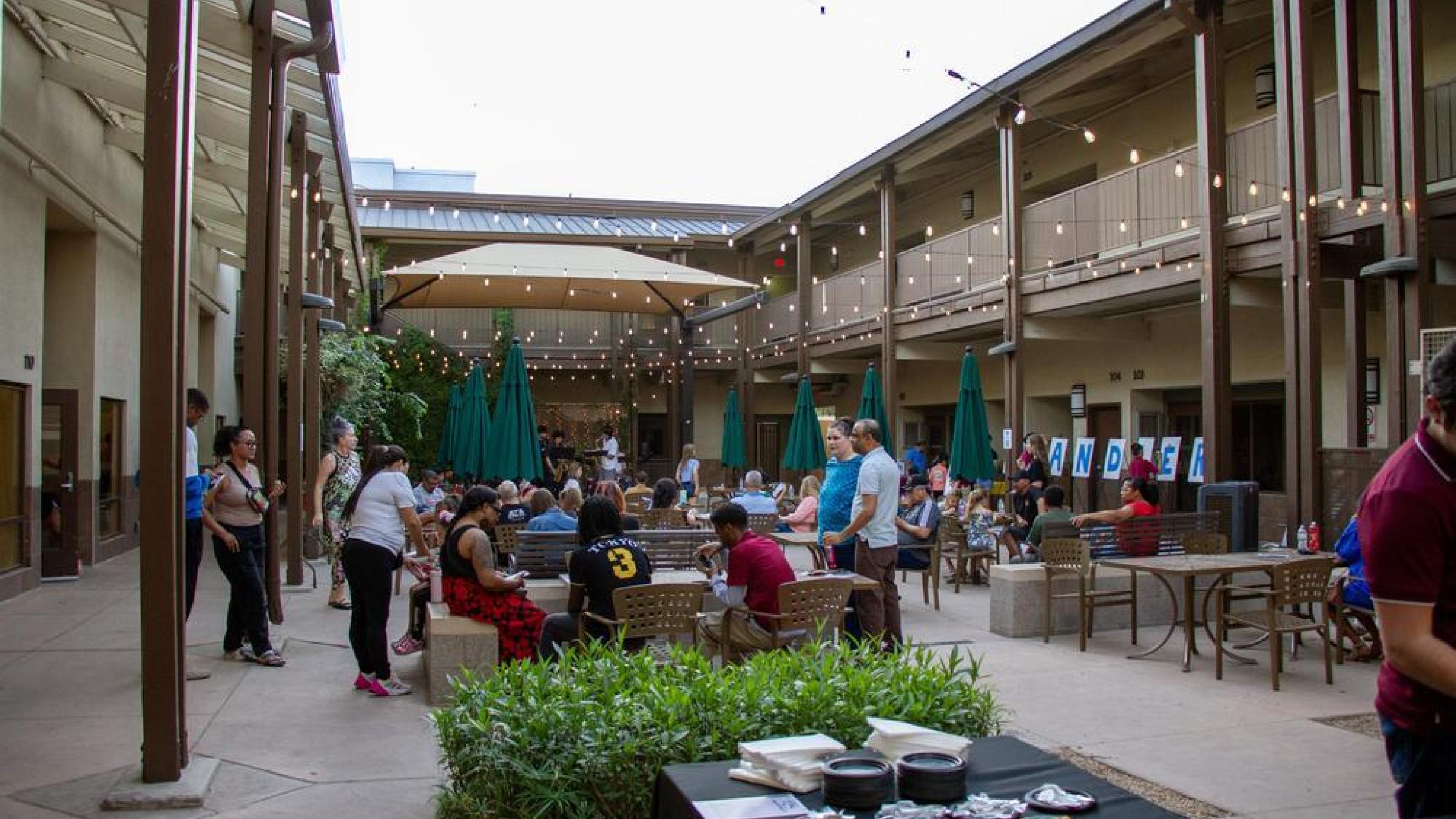 People gathered in courtyard with fairy lights and food