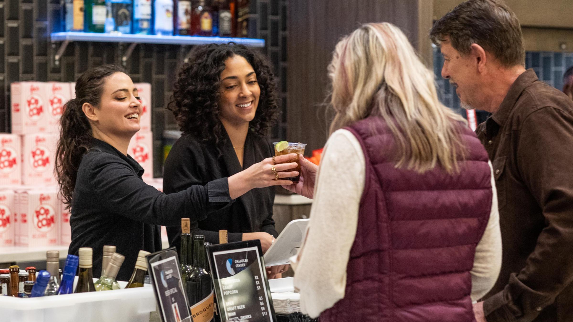 two bartenders serving customers 