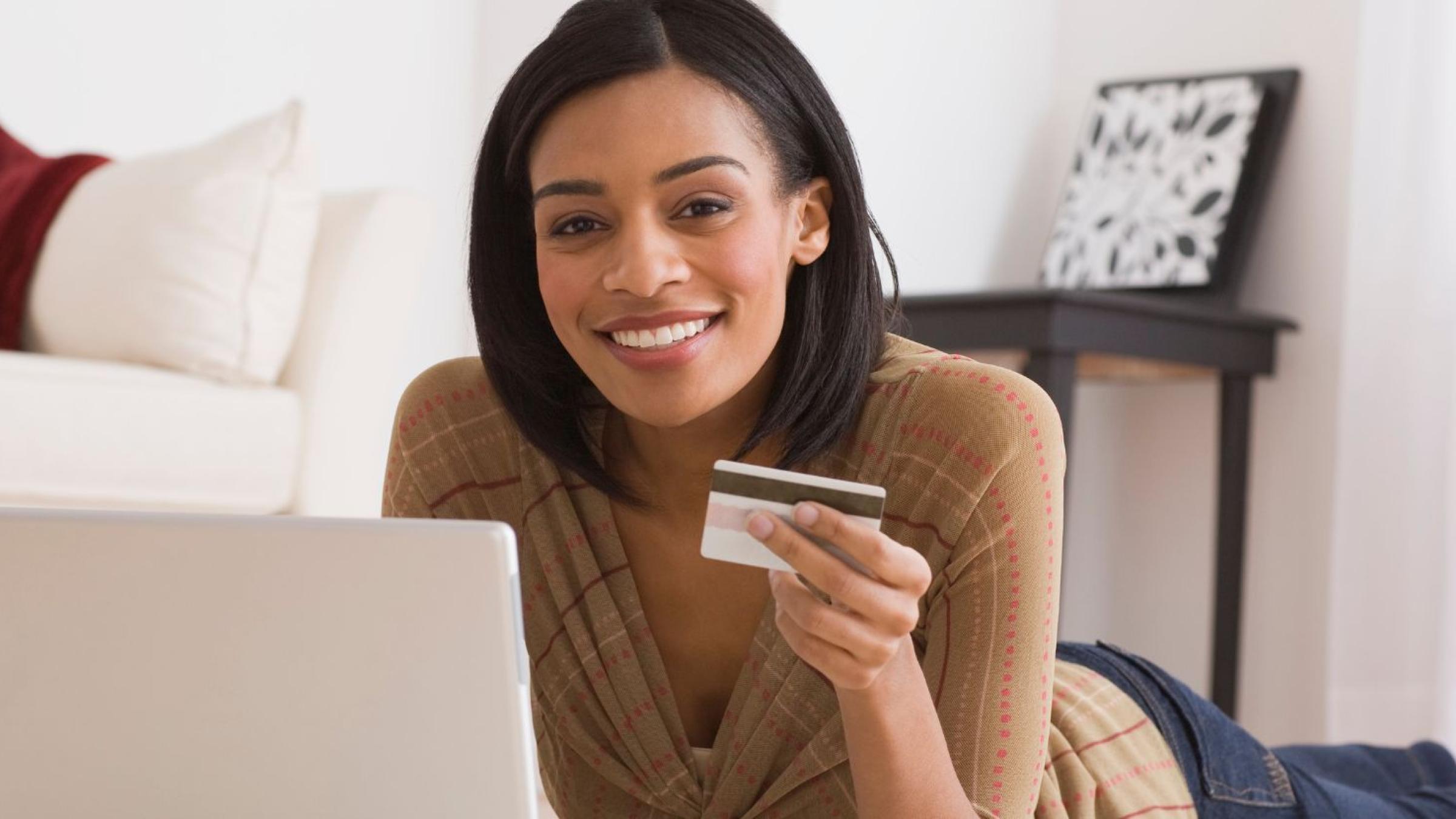 black woman with credit card looking at the computer smiling